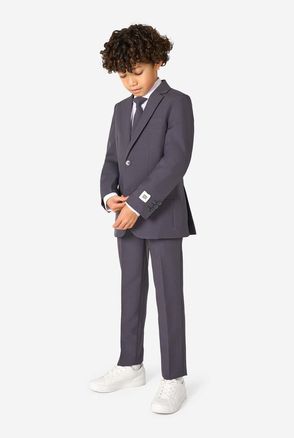 Child wearing a gray suit with white shoes on a white background