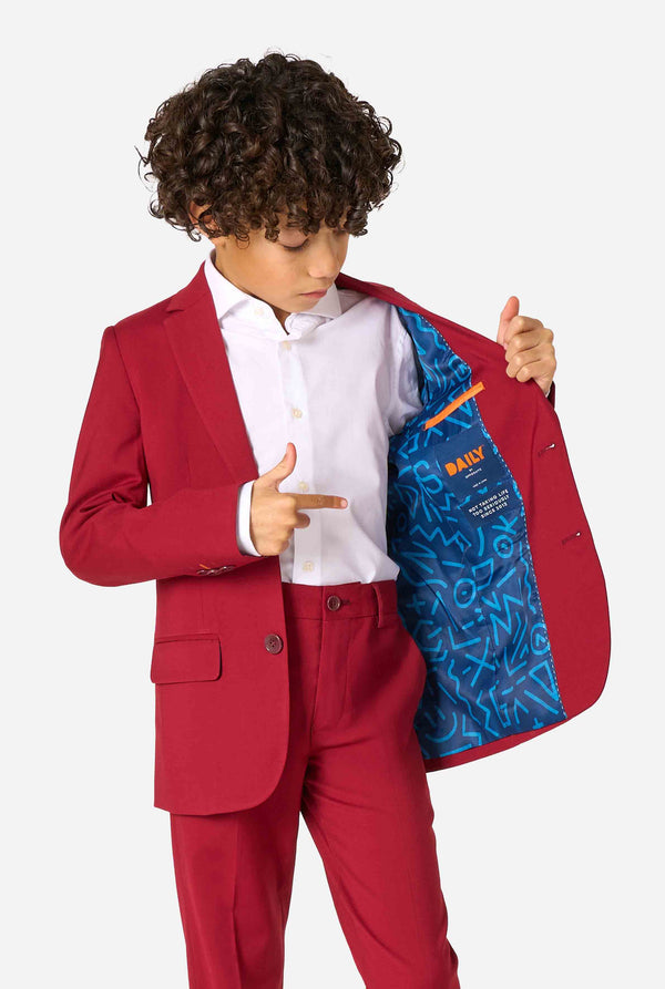 Child in a red suit showing the inside of his jacket with a pattern on a white background