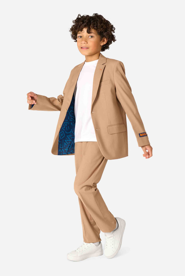 Child wearing a beige suit with a white shirt and white shoes on a white background. Full body image
