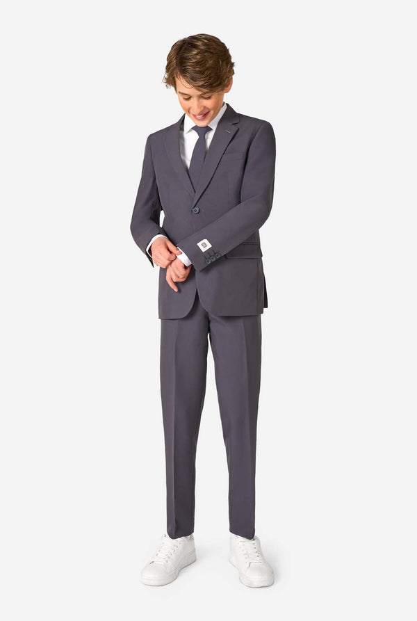 Person wearing a gray suit with a white shirt and white shoes on a white background. Full body image