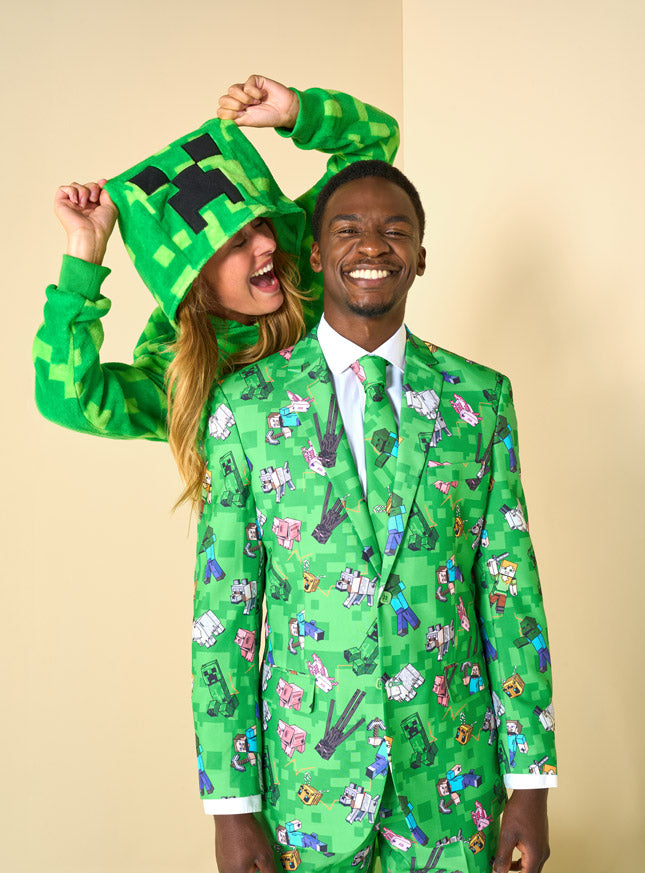 Man wearing a Minecraft suit and a woman wearing a Creeper onesie, standing behnd him an screaming in his ear.