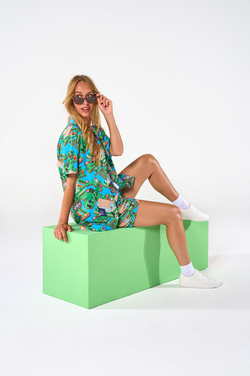 Woman wearing Minecraft summer set sitting on a block against a white blackground