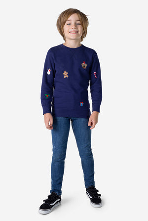 Kid wearing blue Christmas sweater with Christmas icons and blue jeans