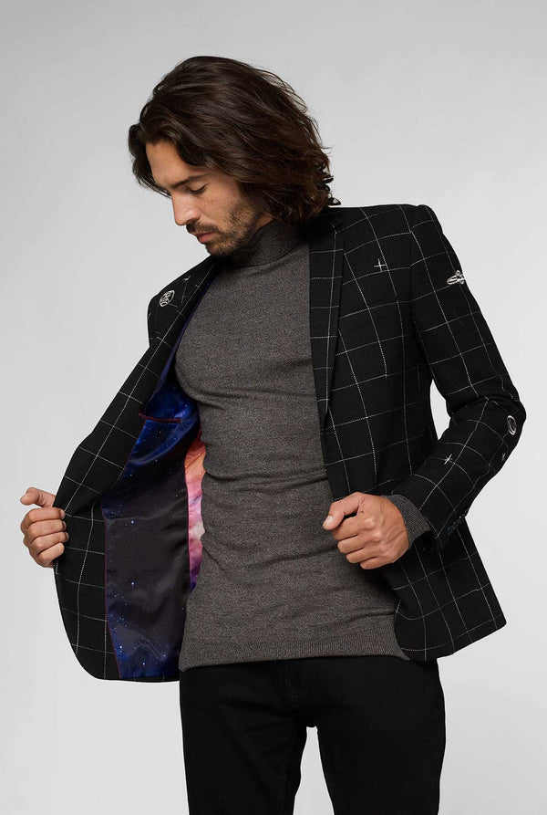 Black casual blazer with white grid pattern worn by man sitting on stool