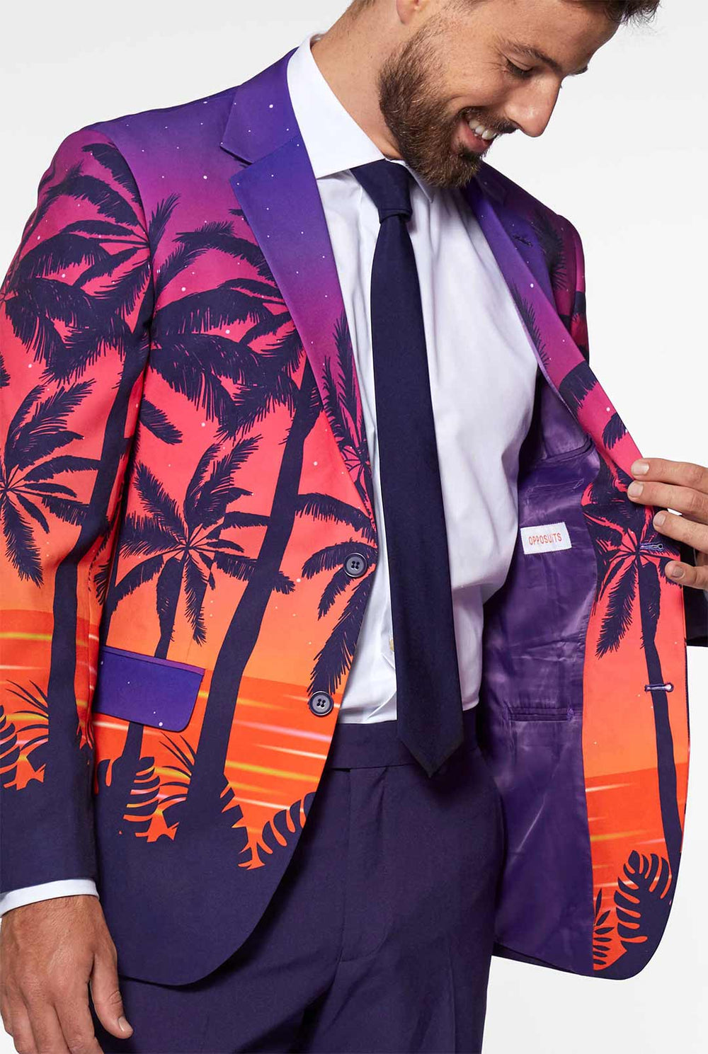 Video of man wearing Suave Sunset men's suit with sunset print, showing suit like a model. Suit consists of blazer, pant and tie.