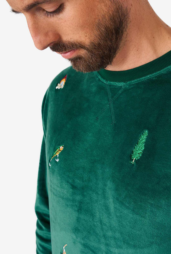 Man wearing velvet green Christmas sweater with Christmas icons