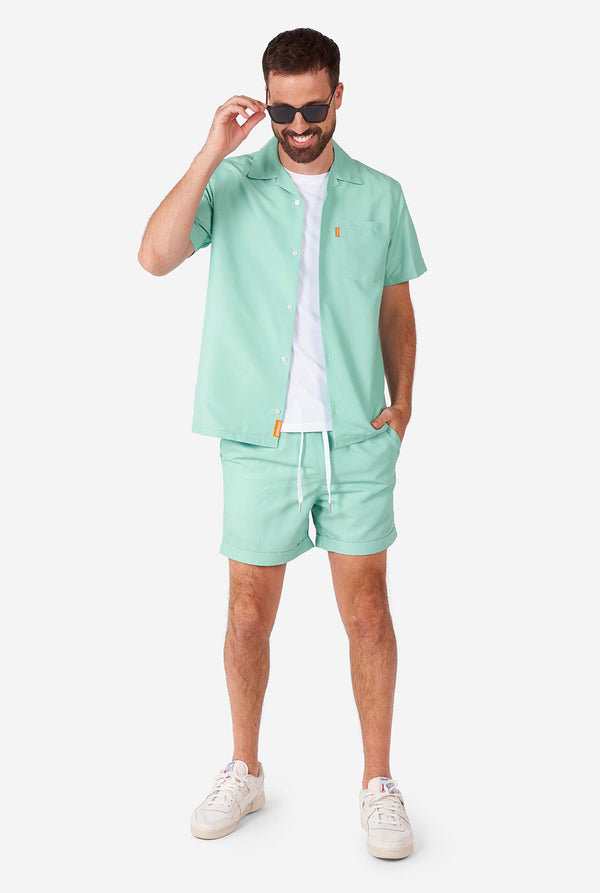 Man wearing green summer set, consisting of short sleeve shirt and shorts.