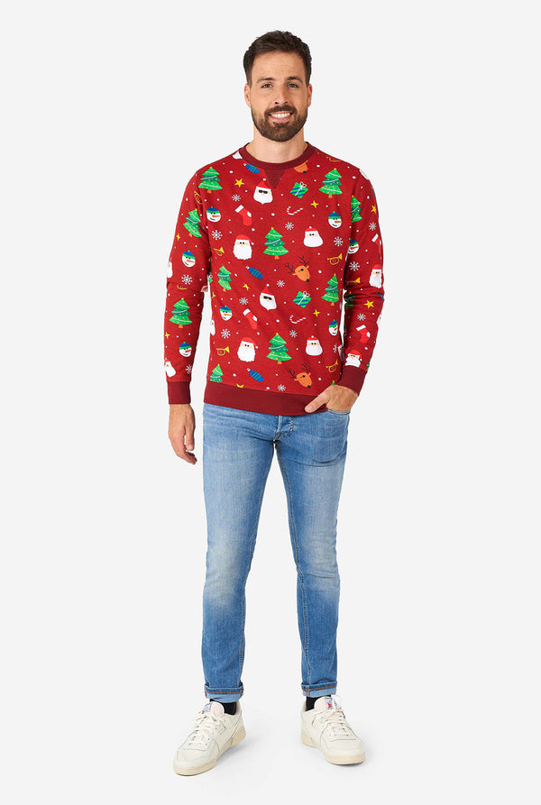 Man wearing red Christmas sweater with colored Christmas icons and blue washed jeans